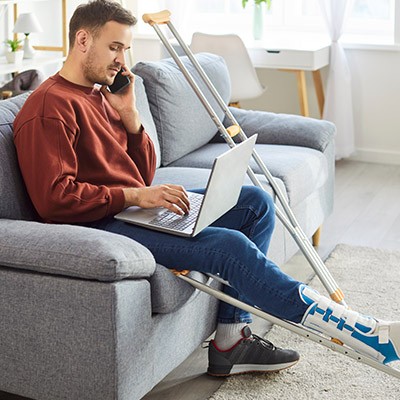 Un homme en incapacité de marcher dans son salon appelant son assurance