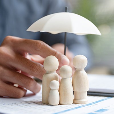 Une illustration d'une famille, représentée en silhouette en bois, sous un parapluie les protégeants.