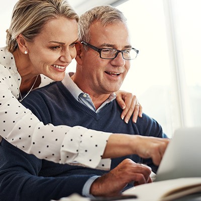 Ordinateur portable et pointez avec un couple heureux à la maison.