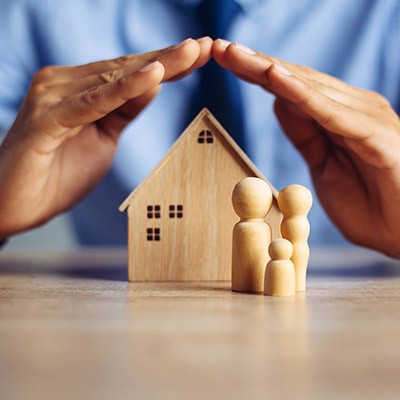 Deux mains protégeant une maison miniature