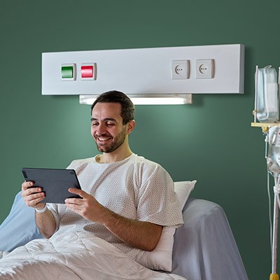 Une jeune homme consultant son assurance hospitalisation sur sa tablette sur son lit d'hôpital